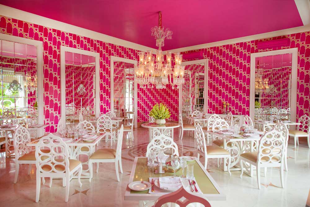 A pink room with tables, chairs, and a chandelier 