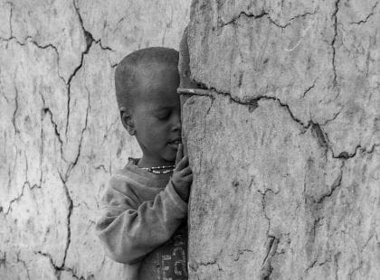 A little boy hiding behind a wall