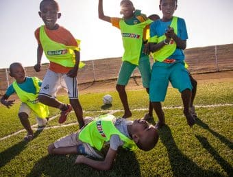 A group of children cheering on a soccer field.