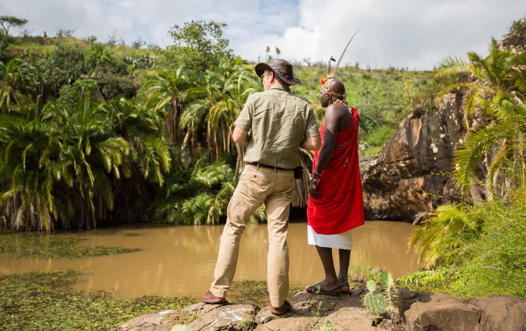 Guide and local stand near pond at Loisaba Conservancy