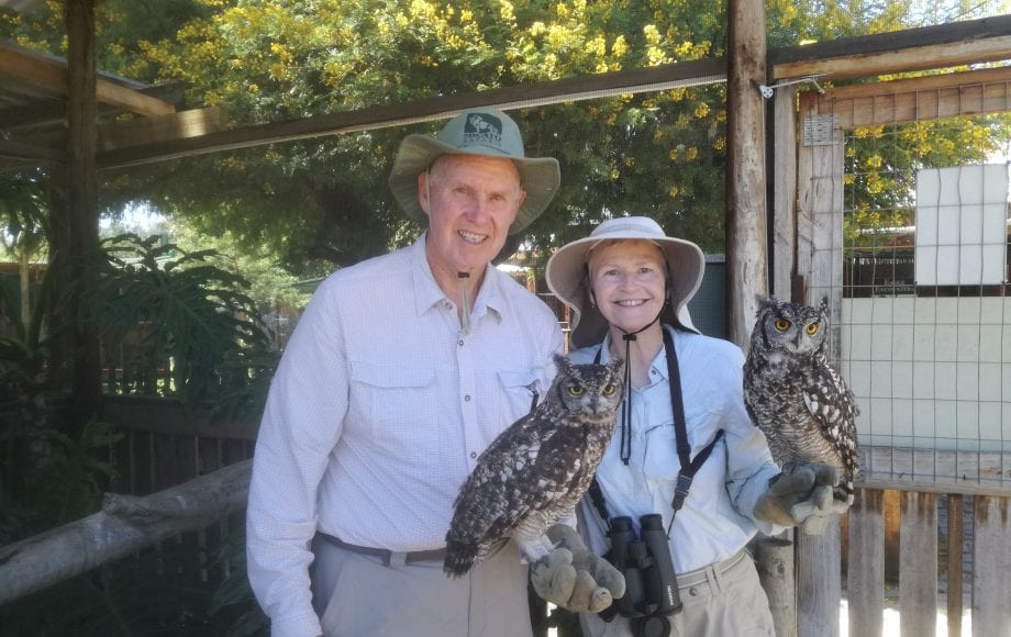 A man and a woman holding owls