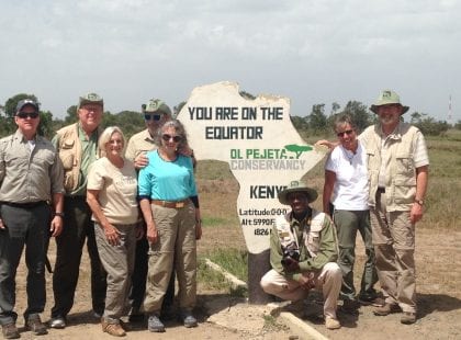 A group in front of a sign indicating the location of the equator