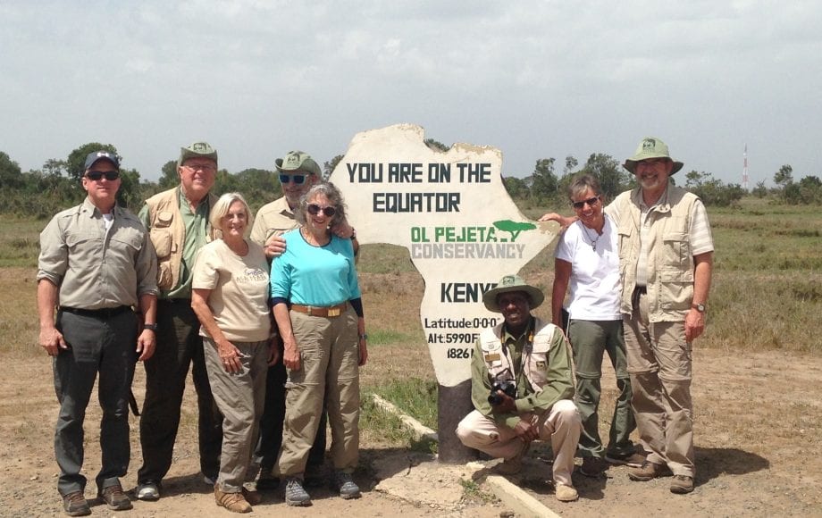 A group in front of a sign indicating the location of the equator