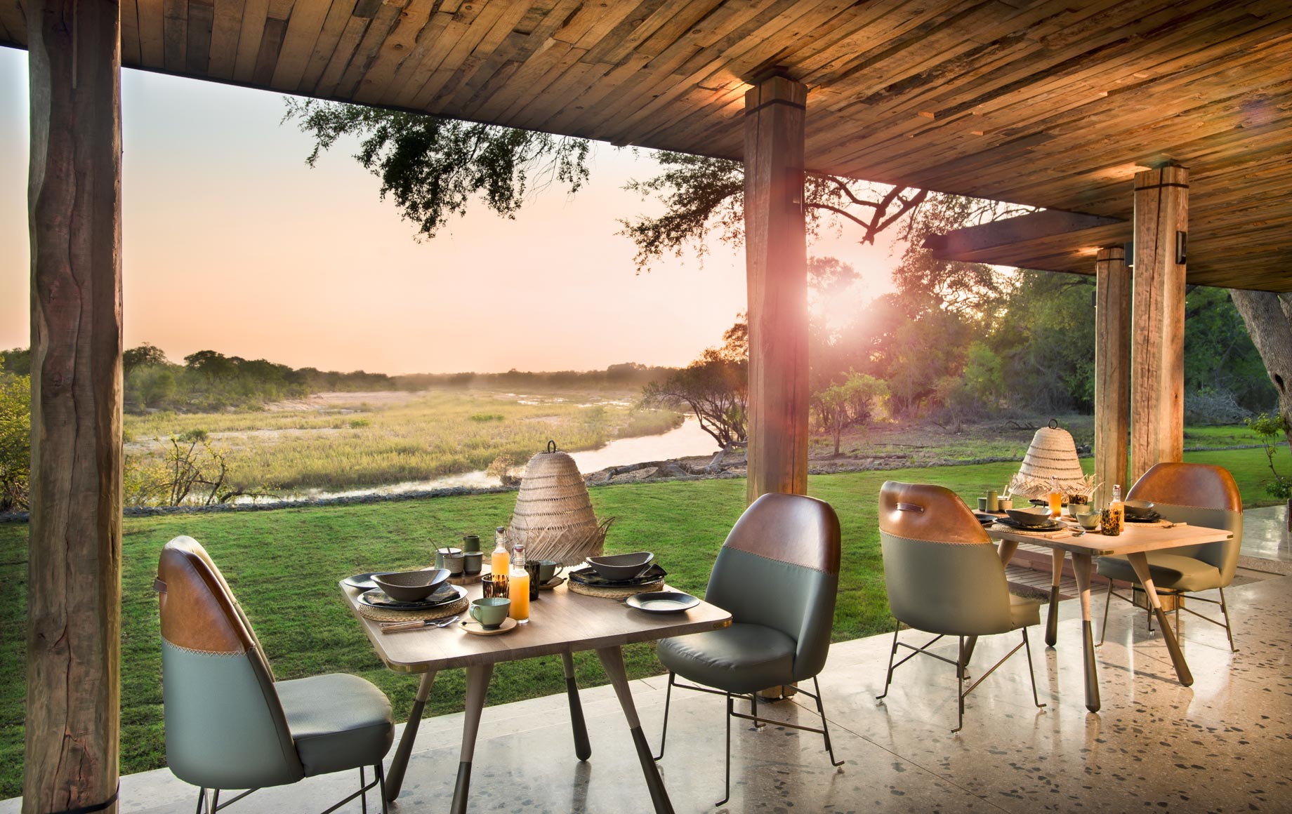 Tables and chairs on deck of Tengile River Lodge at sunset