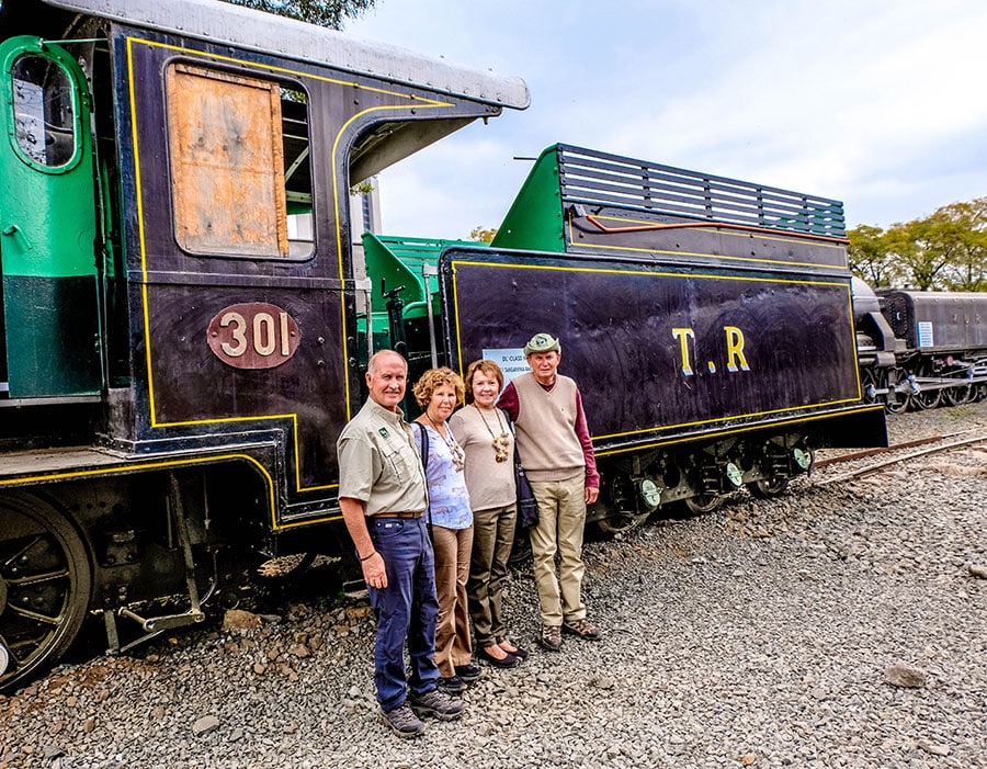 A group of people posing in front of a train