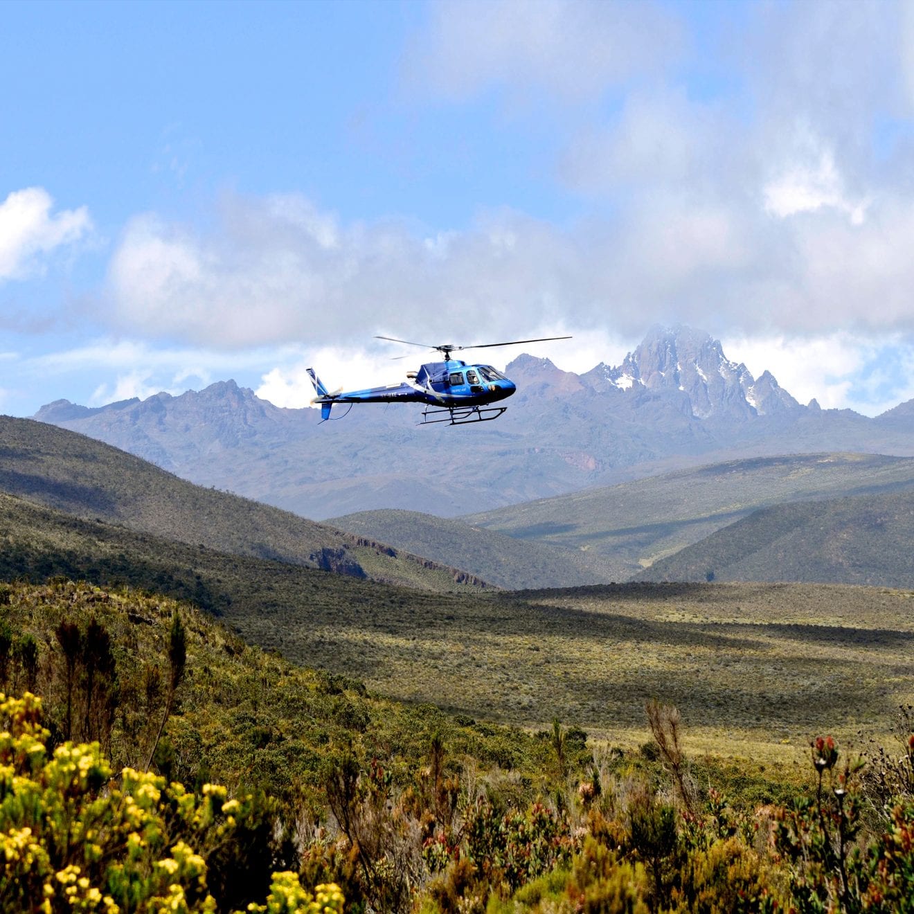 a helicopter flying over the African bush