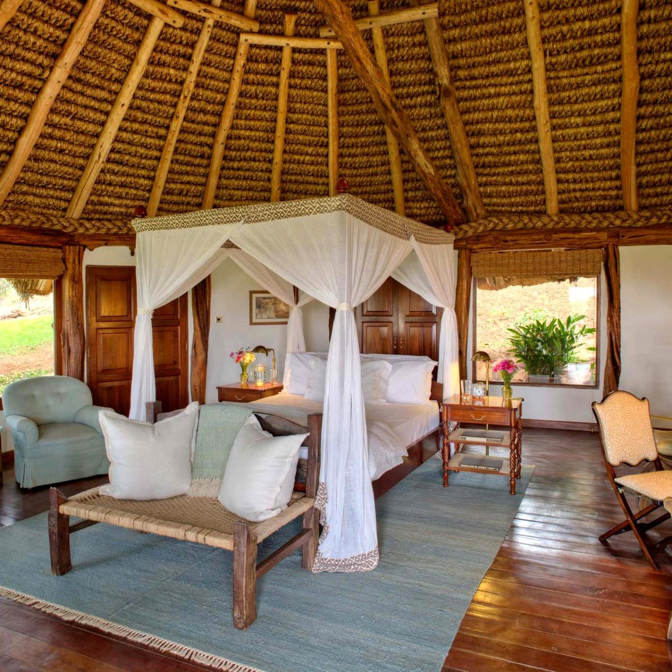 a four post bed in a luxurious room with a wooden ceiling