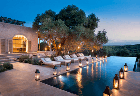 an outdoor patio and pool lit by lanterns at night